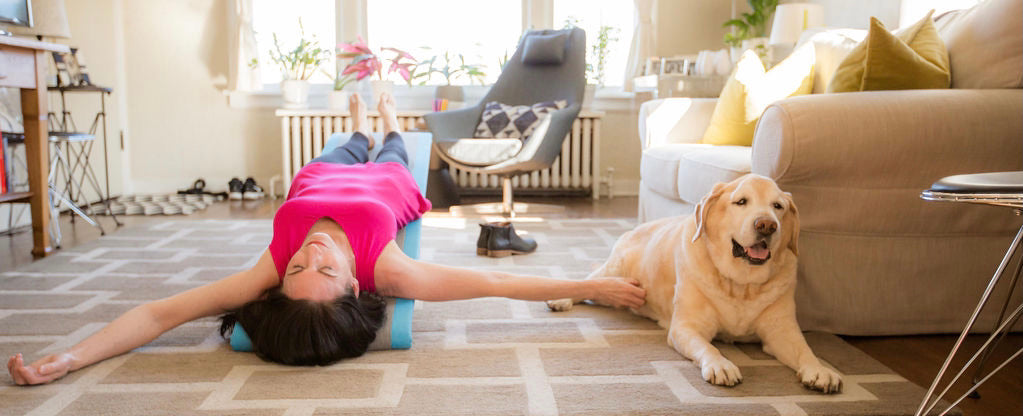 Woman lying on the Lull Incliner, a gentle inversion board, in her living room with her dog